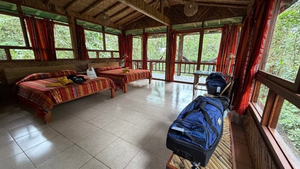 Guest room with two beds and large windows overlooking the forest at San Jorge Milpe, Pichincha, Ecuador.