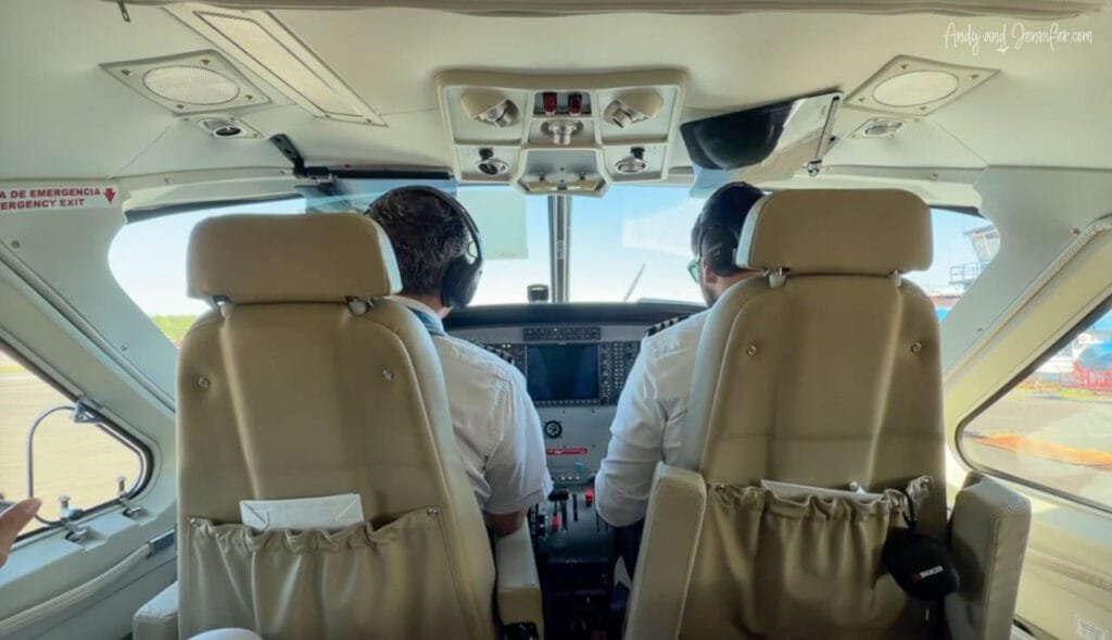The cockpit of a Cessna Caravan viewed from the passenger cabin as two pilots prepare for departure on a regional flight from Changuinola Airport in Panama.