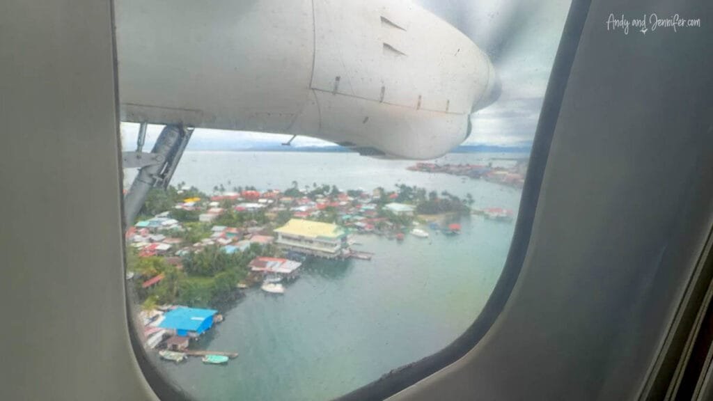 View from a small propeller plane descending into Bocas del Toro, Panama, above colorful waterfront homes and tropical islands.