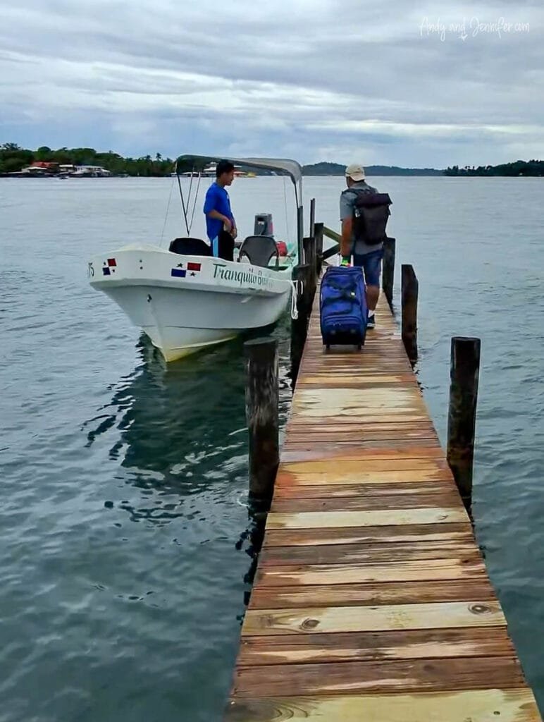 Guest boarding a Tranquilo Bay boat from a wooden dock in the Bocas del Toro archipelago of Panama.