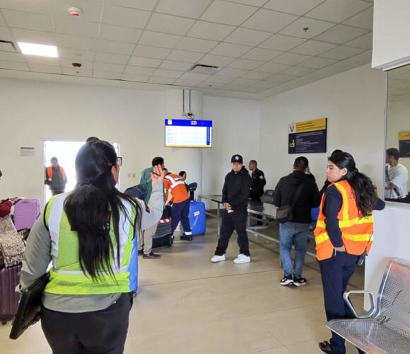 Passengers and airport staff waiting during a security screening at an airport in Ecuador.