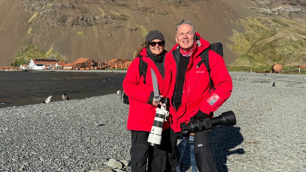 Andy and Jennifer with camera gear on the shoreline at Stromness, South Georgia, with the historic whaling station behind them.