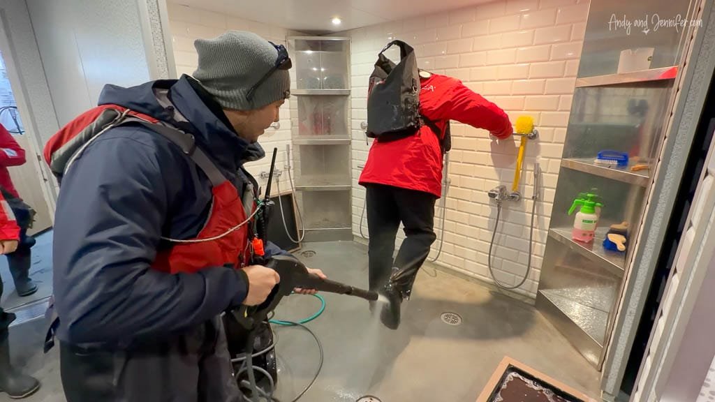 Expedition staff rinsing a passenger’s boots to remove mud and debris after a shore landing aboard Silver Wind.