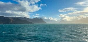 Mountainous coastline and turquoise waters of Jason Harbour on South Georgia under clearing skies.