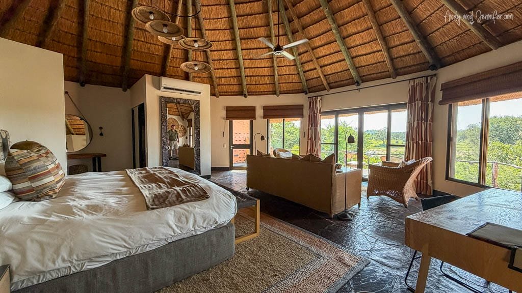 Spacious guest suite at MalaMala Game Reserve with a thatched roof, bedroom and sitting area overlooking the bush.