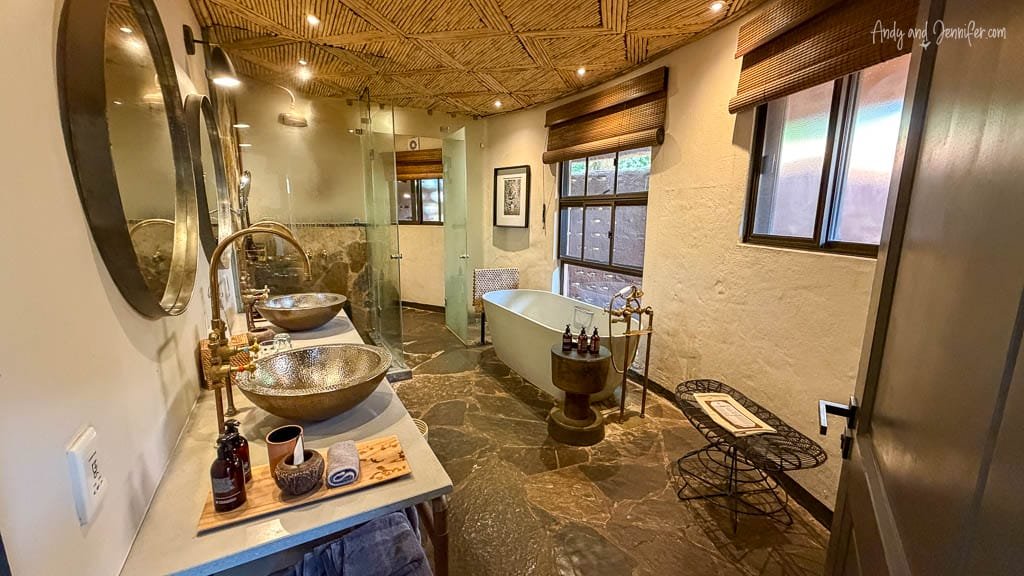 Bathroom at MalaMala Game Reserve with twin basins, a freestanding bathtub and walk-in shower.
