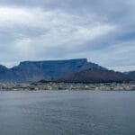 Cape Town beneath Table Mountain, Lion’s Head and Signal Hill, viewed across Table Bay under cloudy skies.