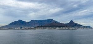 Cape Town beneath Table Mountain, Lion’s Head and Signal Hill, viewed across Table Bay under cloudy skies.