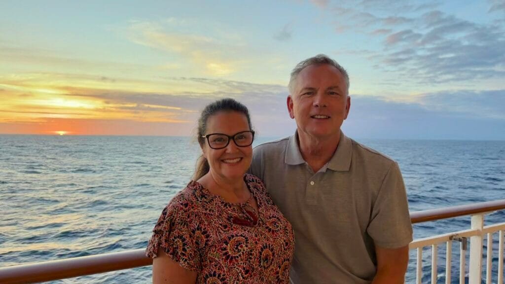 Andy and Jennifer posing in front of a sunset on the Norwegian Spirit