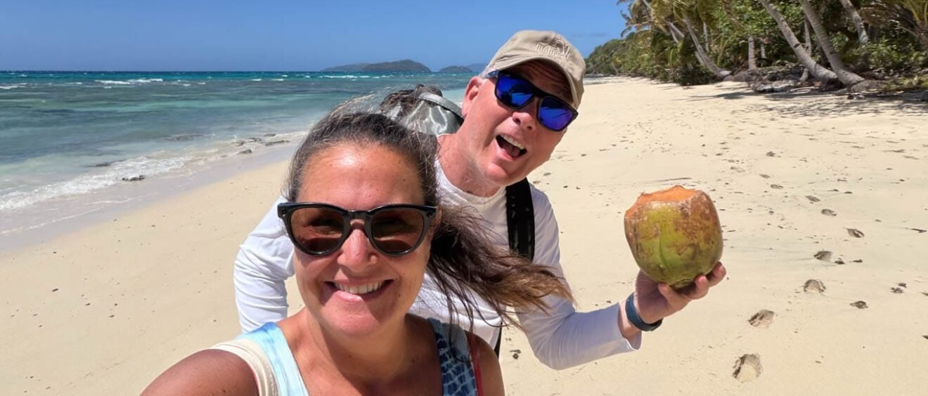 Jennifer and Andy on a deserted white sand beach next to turquoise water in Dravuni, Fiji