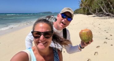 Jennifer and Andy on a deserted white sand beach next to turquoise water in Dravuni, Fiji